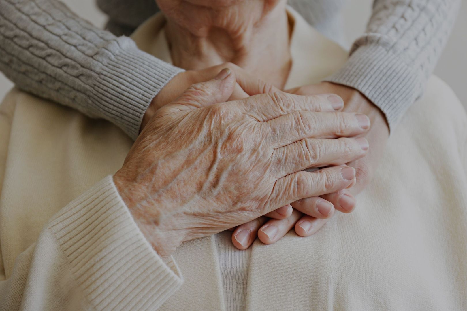 Ältere Dame hält die Hand einer Pflegerin